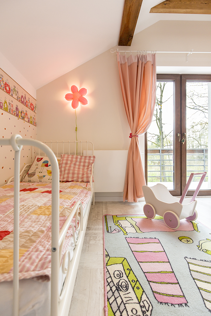 Dormitorio infantil muy luminosa de colores pasteles rosas y con iluminación de acento en forma de flor