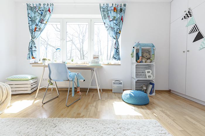 Dormitorio infantil muy luminoso con cortinas azules corridas y una lámpara de escritorio