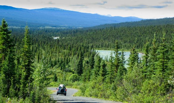 Paisaje de Canadá con montañas, bosque y una carretera con un coche de viaje