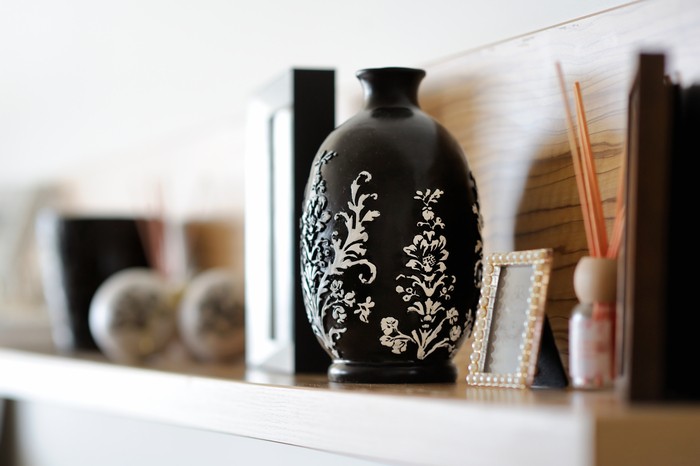 jarrón negro con dibujos florales colocado en una estantería
