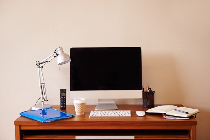 zona de teletrabajo con escritorio con portátil, flexo, libreta, teléfono y demás objetos