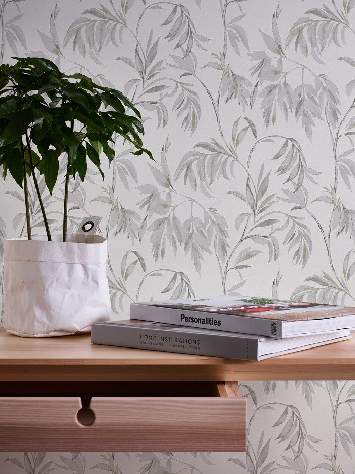 mesa con libros y una planta y de fondo una pared con papel pintado de motivos florales