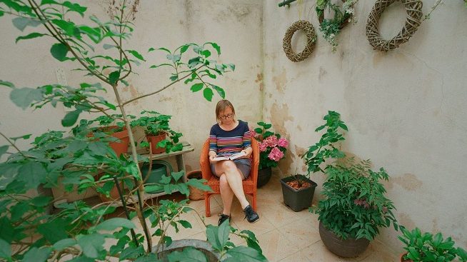 Mujer leyendo en su jardín con plantas