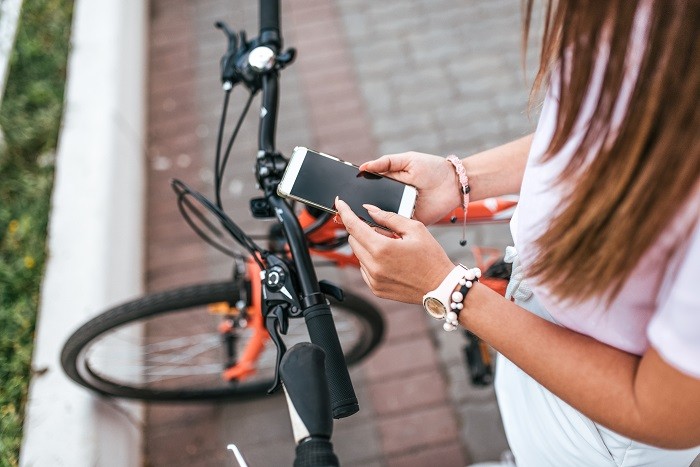Chica con bicicleta usando su móvil smartphone