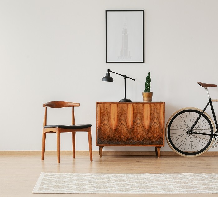 Espacio con un mueble antiguo con una silla antigua y una bicicleta con espejo y alfombra