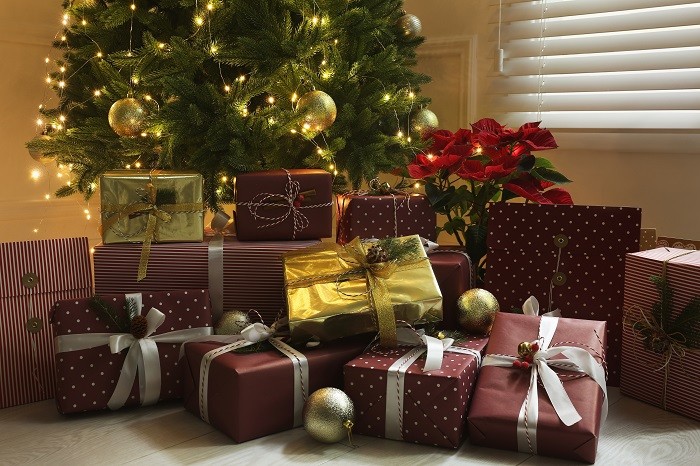 Casa con su árbol de Navidad con muchos regalos y una flor de pascua