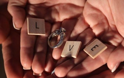 manos abiertas con letras y un anillo de compromiso para regalar en San Valentín