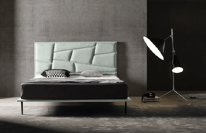 dormitorio con cama con un cabecero geométrico tapizado en gris