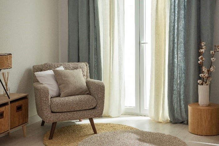 salón con sofá, alfombra natural y cortinas
