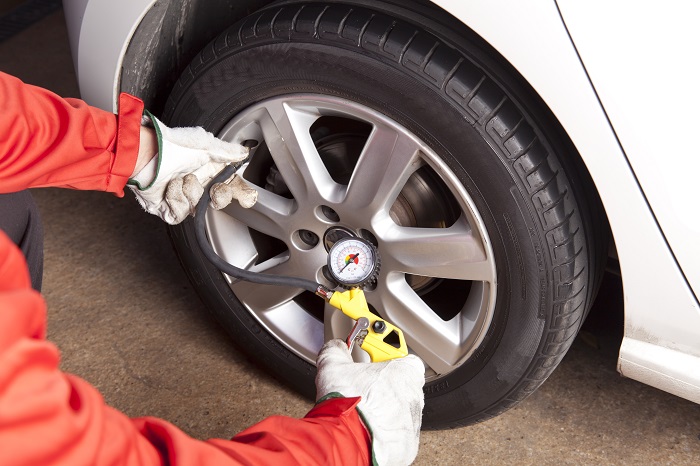 Persona comprobando la presión de los neumáticos de su coche