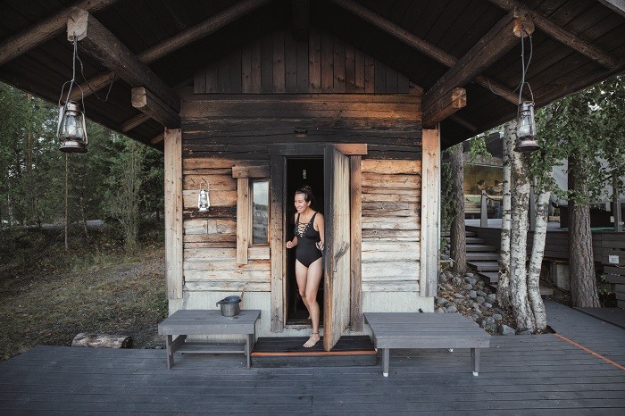 mujer saliendo de una sauna entre árboles