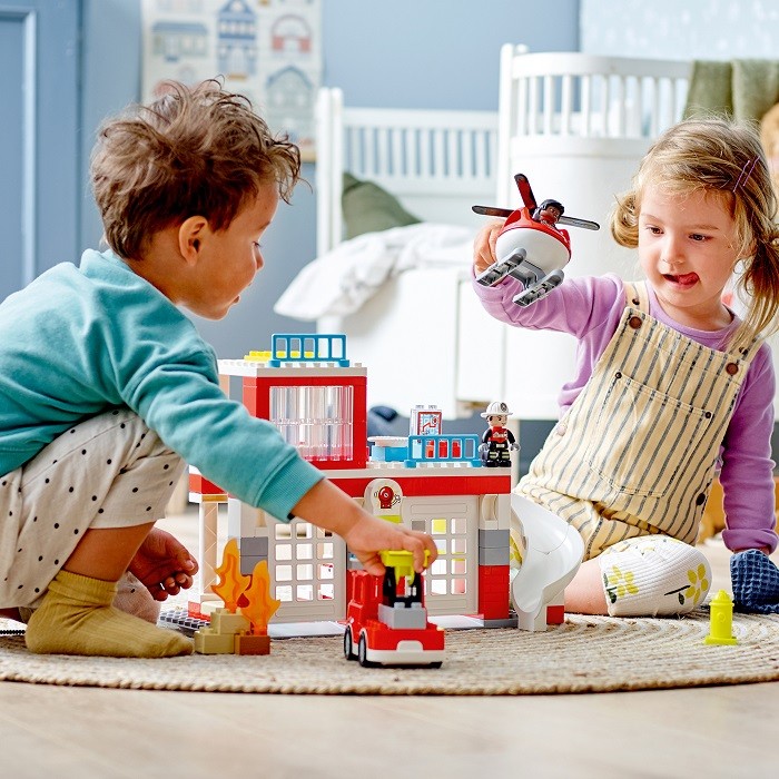 niño y niña jugando con lego bomberos