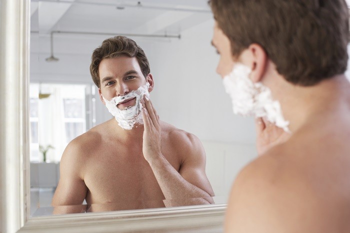 Hombre aplicándose crema de afeitar en la cara