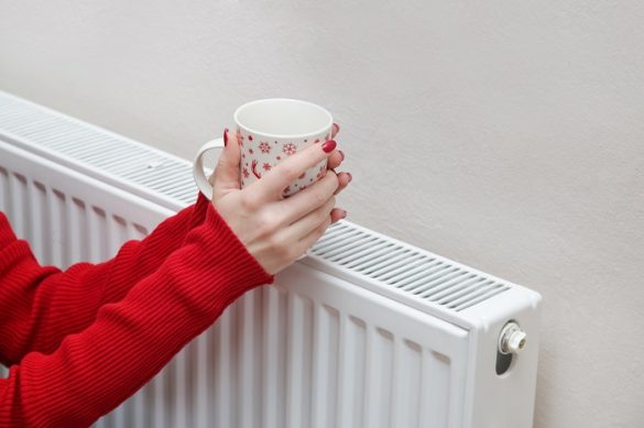 manos de una mujer con un café sobre un radiador caliente