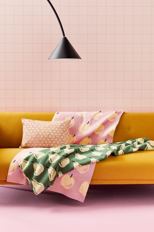 sofá mostaza con cojín estampado y toallas rosas
