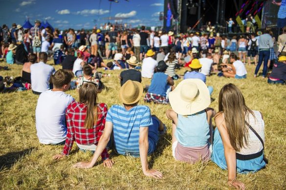 Grupo de personas sentadas en el suelo escuchando un festival de fondo