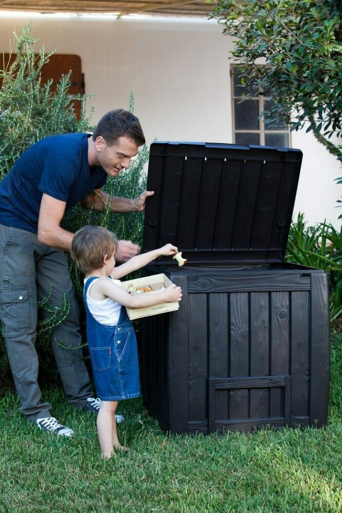 Padre con su hijo en un compostador en el jardín de su casa