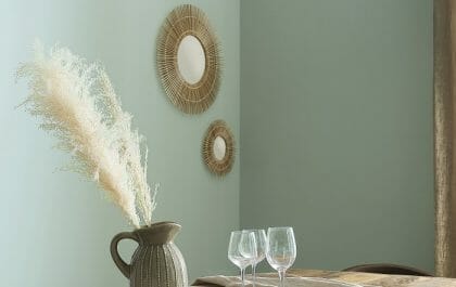 Salón con mesa puesta y pared verde con espejo moderno