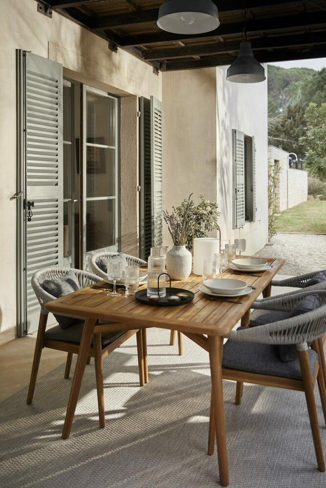 mesa y sillas en el exterior de un hogar con techo para protegerse de lluvias