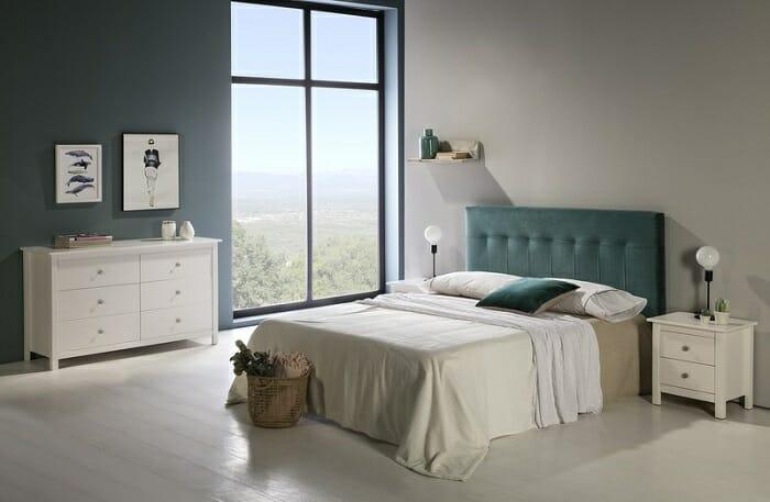 Dormitorio con mesilla y cómoda blancas con cajones y cabecero de color verde