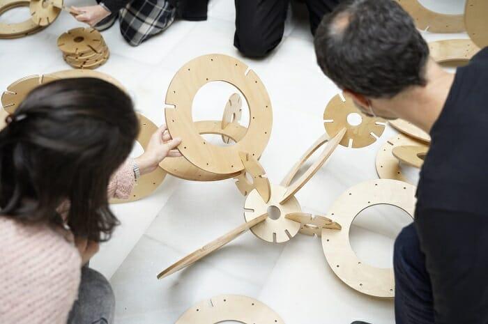 Personas en un taller con objetos de madera en Mugak Bienal de Euskadi