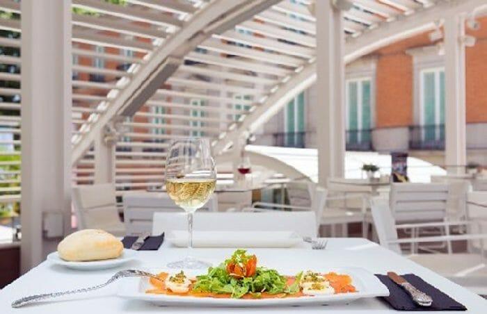 mesa con un plato de comida y una copa de vino de la terraza del museo thyssen en Madrid