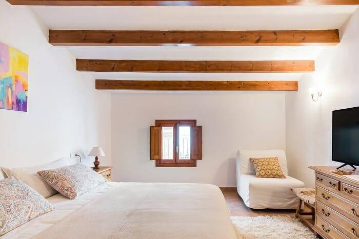 Interior de una habitación de un refugio en Jávea con vigas de madera en el techo