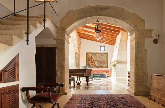 Interior hall de una antigua casa rural restaurada. Tiene alfombra, arco de medio punto y escalera.