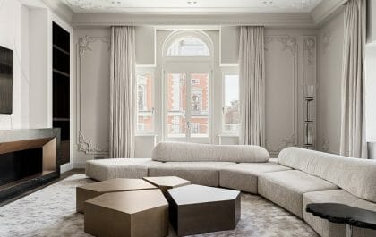 Salón con gran sofá blanco y mesita de madera con un diseño clásico de interiorismo