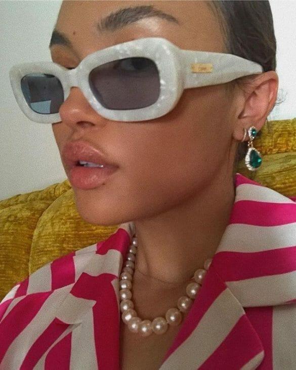 Mujer con collar de perlas y gafas de sol con borde blanco