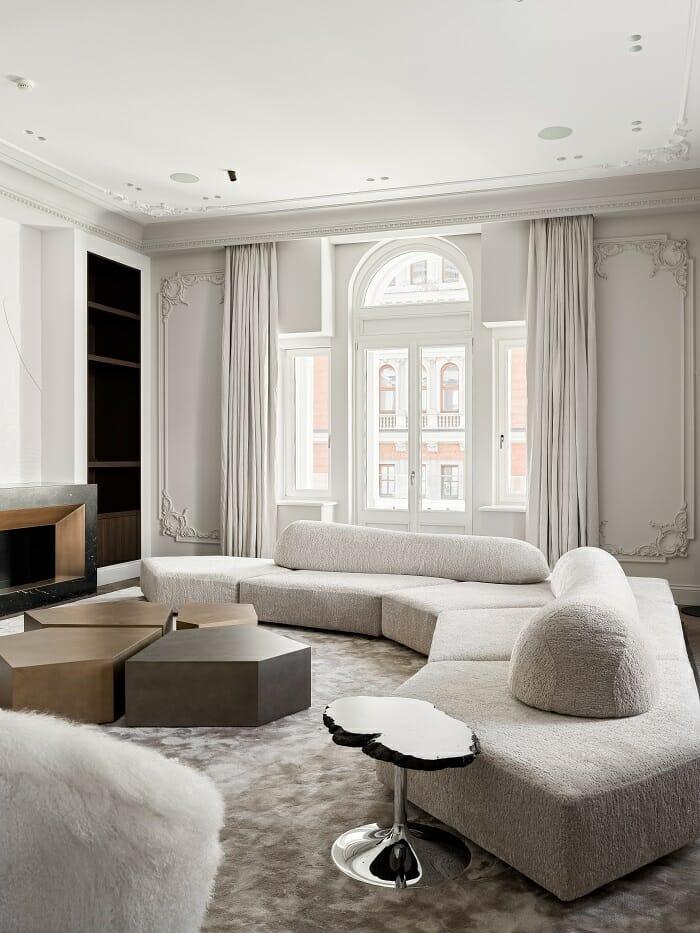 Salón con gran sofá blanco, mesita de madera de diseño y una pequeña mesita de madera, diseño clásico