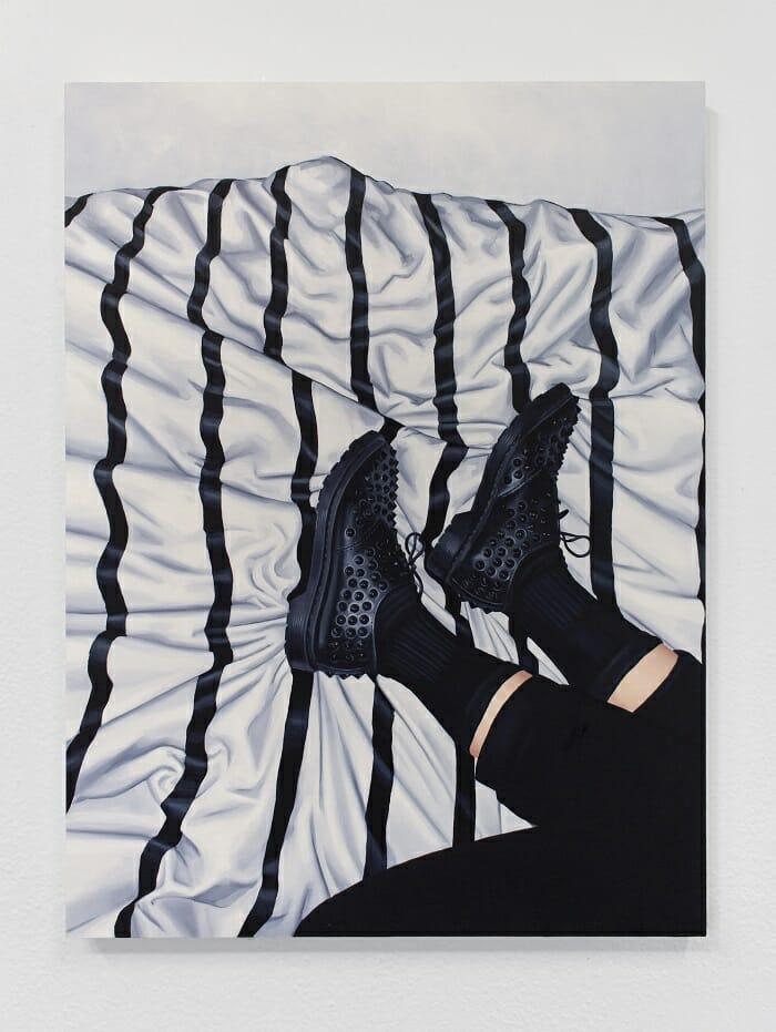 Piernas con pantalones negros y zapatos encima de una tela blanca sobre rayas negras