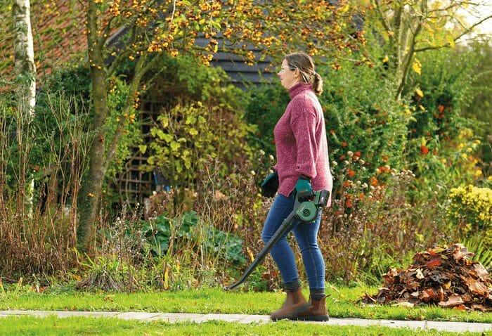 Mujer con un soplador de Bosch para recoger las hojas de su jardín