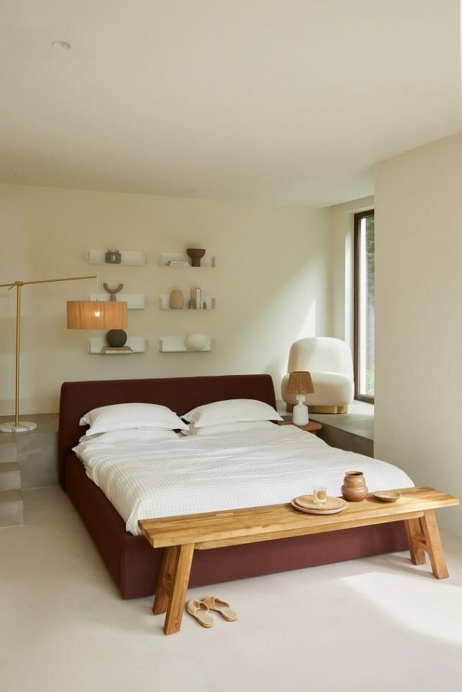 Dormitorio con una decoración en blanco y madera en el mueble banco a pie de la cama