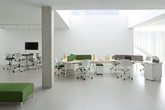 Espacio de oficina en blanco y verde con mesas y sillas ergonómicas