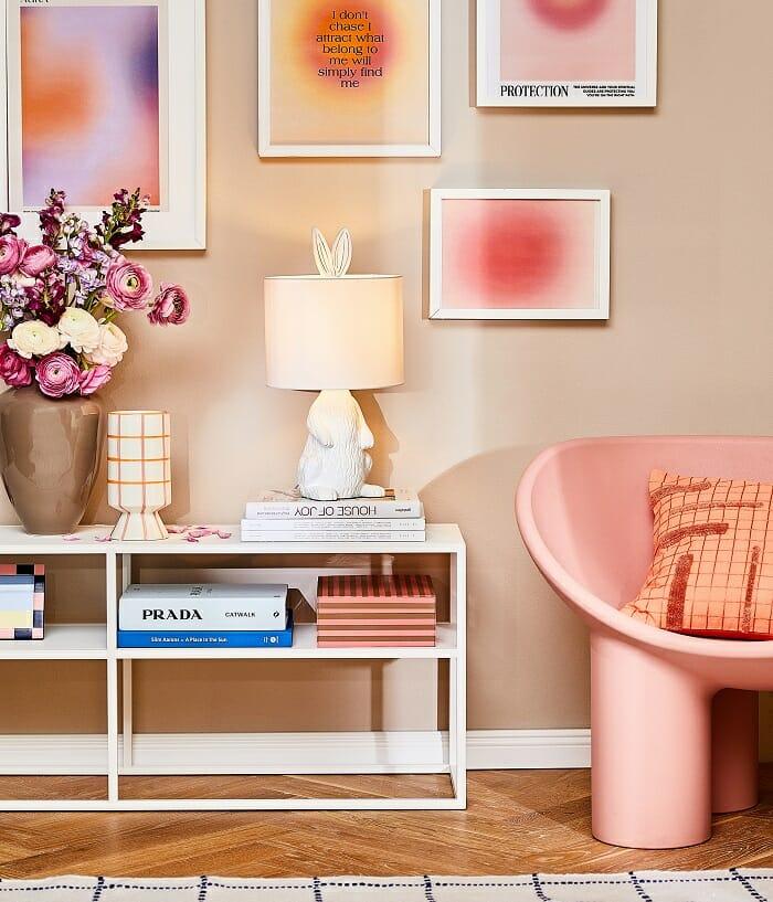 accesorios y detalles estilo Barbiecore como cuadros, libros, sillón rosa, lámpara