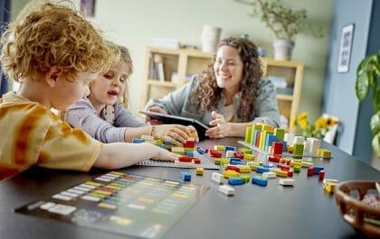 Dos niños con un adulto jugando al LEGO Braille Bricks 2024