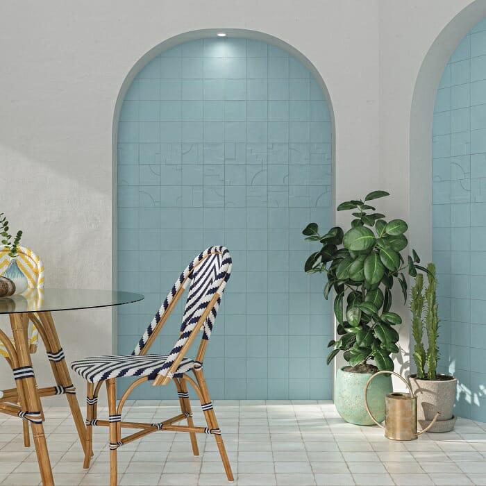 Zona de estar con silla con una pared con piezas de cerámica en color azul claro