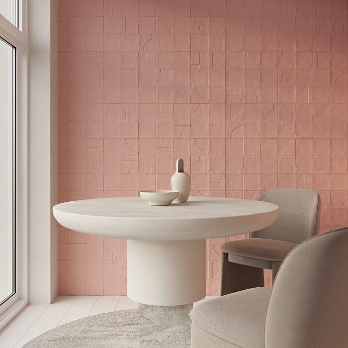 Zona de estar con mesa y silla en color beige y pared de cerámica con relieve en tono rosa claro