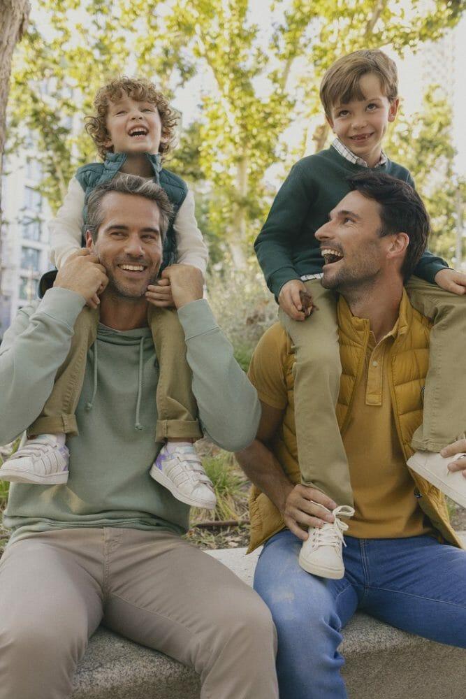 Pareja de padres con sus hijos a los hombros con un estilo de ropa de la marca Scotta