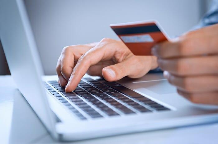Manos con una tarjeta de crédito frente a un portátil para hacer una compra online