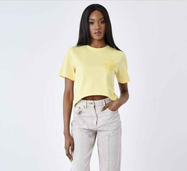 Modelo con ropa de Rosalía vaqueros y camiseta amarilla