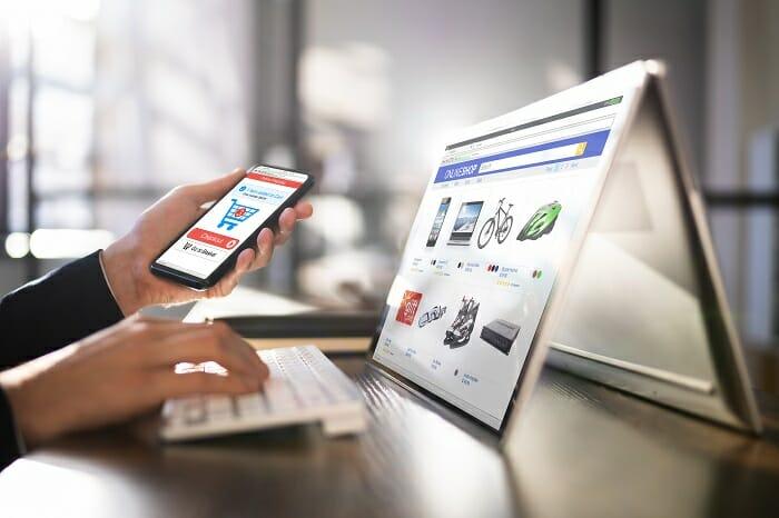 Persona con un ordenador y un móvil en la mano dispuesto a hacer una compra online