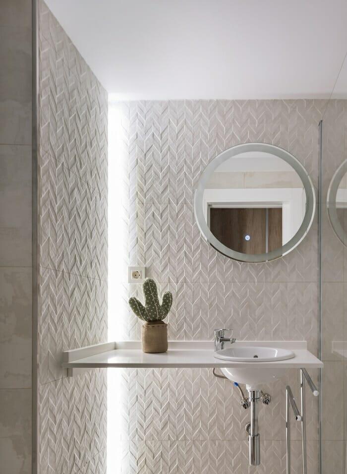 Lavabo con espejo redondo con pared en beige y luz LED