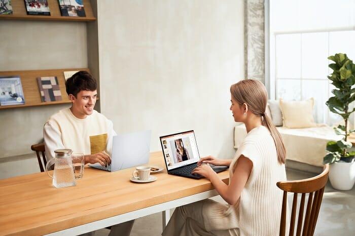 Mujer y hombre hablando en la mesa de una oficina con un portátil encima de la mesa de la marca ASUS