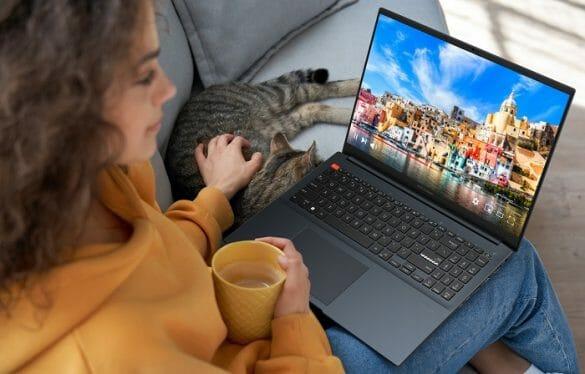 Chica con portátil en sus rodillas mirando ciudades con un gato en el sofá