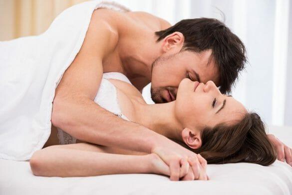 Una pareja en la cama agarrados y tapados con la sábana