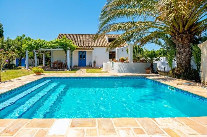 Casa blanca con piscina y palmera en su exterior