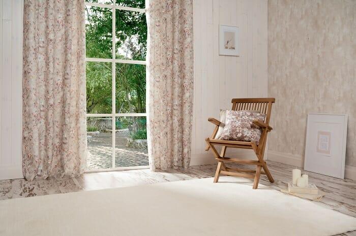 Habitación con una silla de madera y unas cortinas de flores