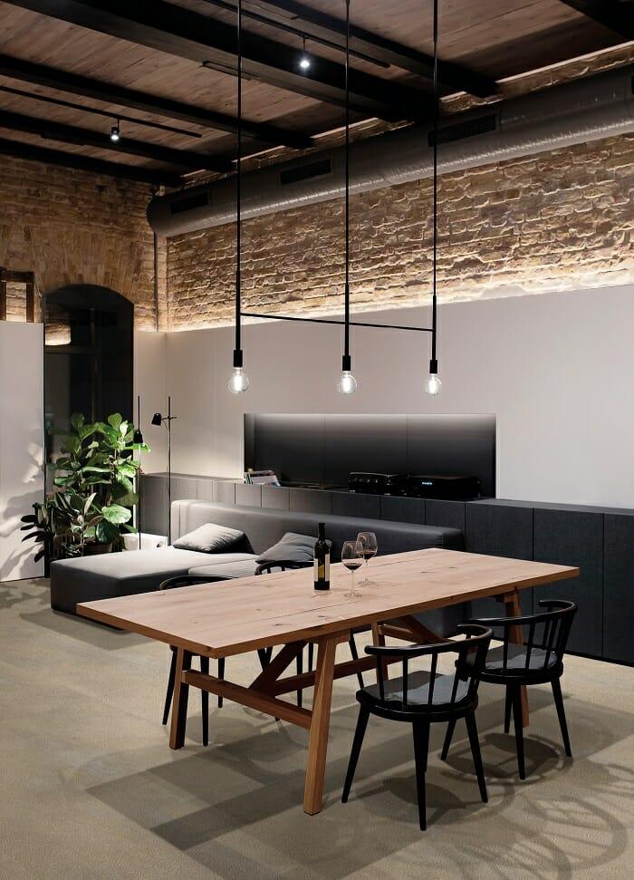 Salón con estilo industrial con lámparas colgantes y colores grises con madera